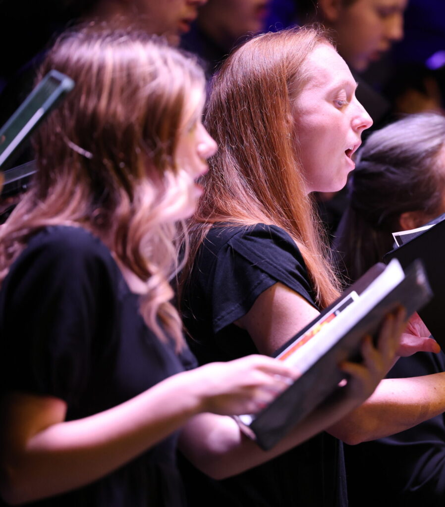 Two young women in the Jefferson College Choir singing in a concert setting